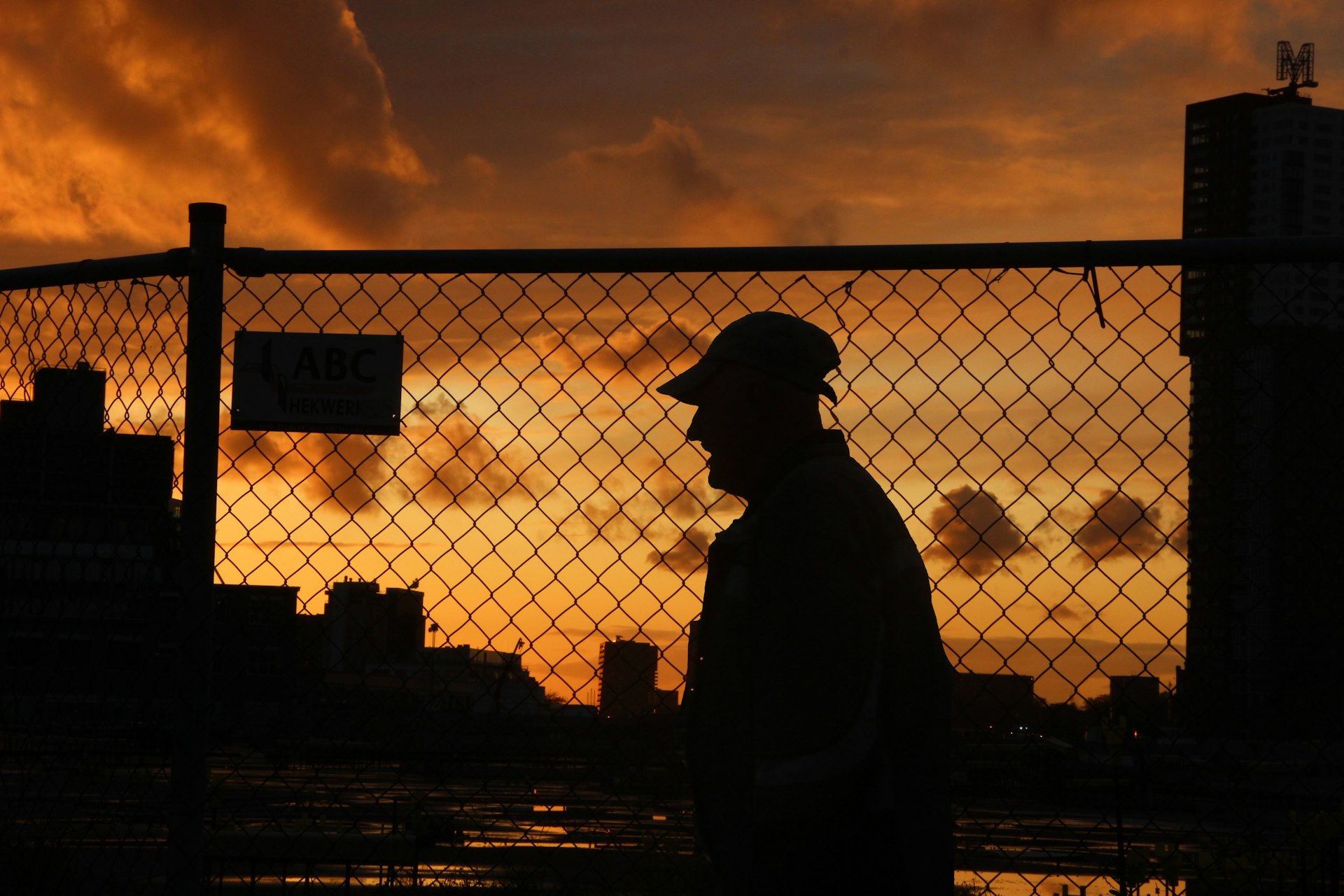 Construction worker silhouetted against a dramatic sunset sky